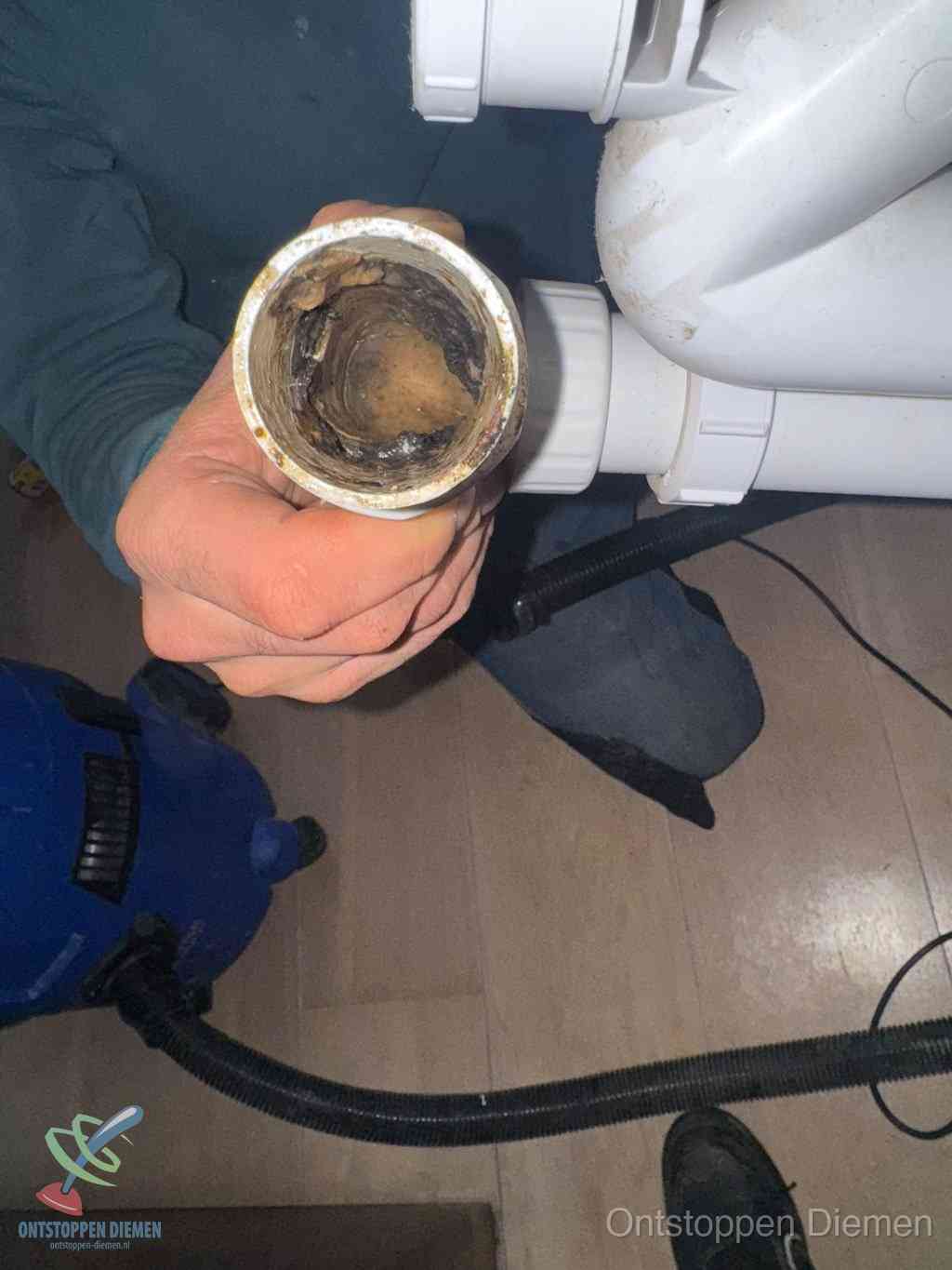 Een losgekoppeld afvoerbuisstuk dat van binnen volledig is dichtgeslibd, het gevolg van een verstopping te lang laten zitten in Diemen