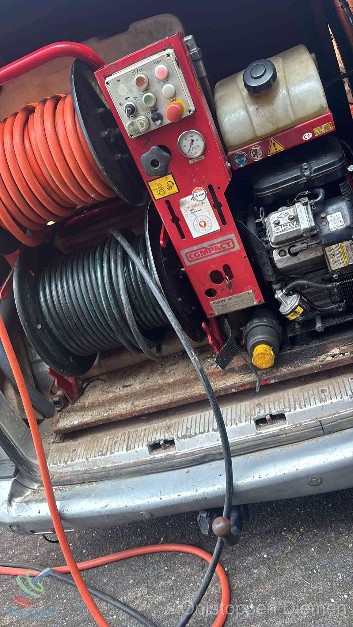 Een rood hogedruk-rioolreinigingstoestel met slangen in de laadbak van de bedrijfsbus, apparatuur voor een hardnekkige wc-verstopping in Diemen