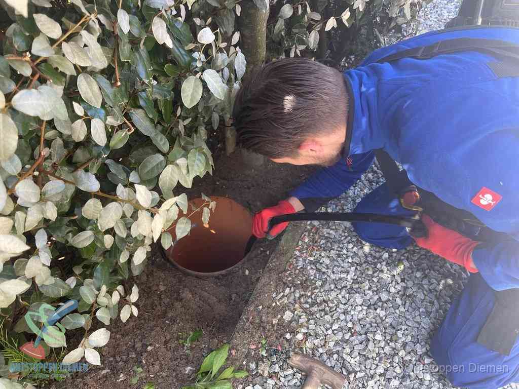 Monteur reinigt een rioolput met een slang, periodieke rioolreiniging in Diemen