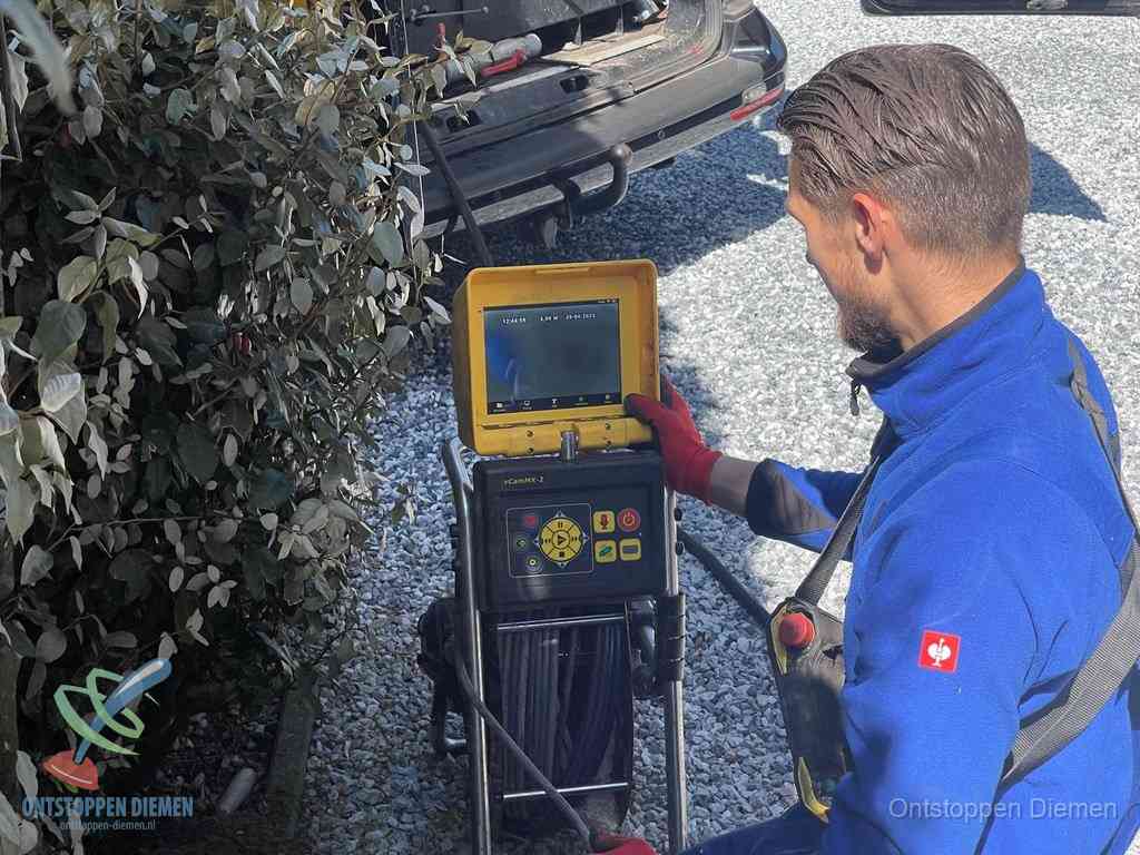 Monteur bedient een rioolinspectiecamera met monitor voor rioolinspectie in Diemen