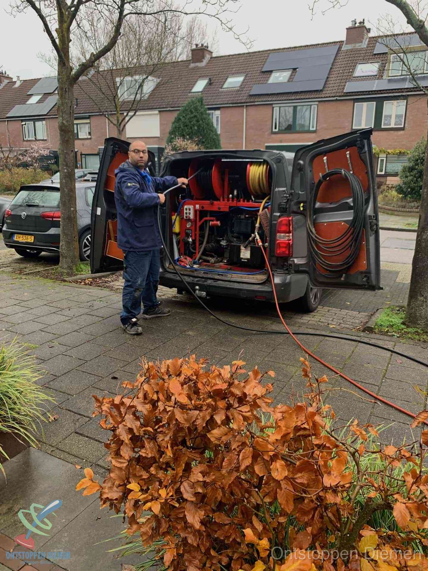 Monteur met rioolreinigingsbus levert rioolservice in de wijk in Diemen