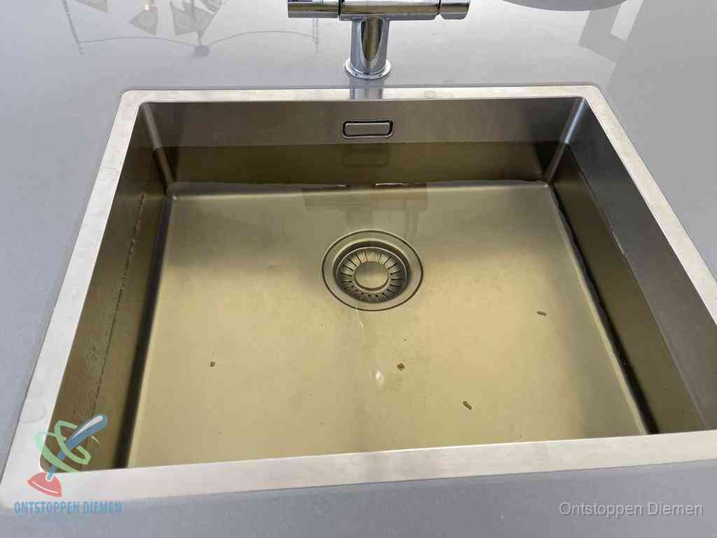 Stilstaand water in een rvs spoelbak dat niet wegloopt, een duidelijk signaal van een gootsteenverstopping in Diemen