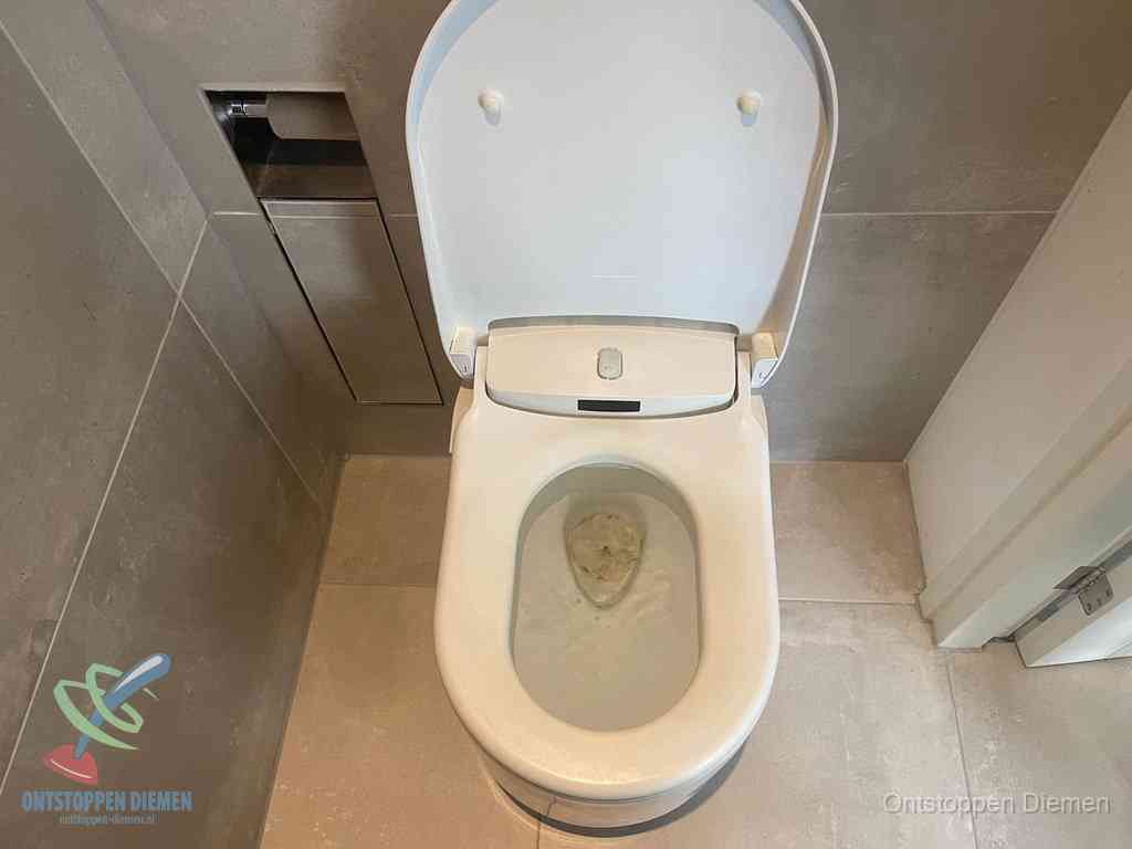 Een wit hangtoilet waarin een prop wc-papier op het water blijft drijven, een duidelijk signaal van een verstopte wc in Diemen