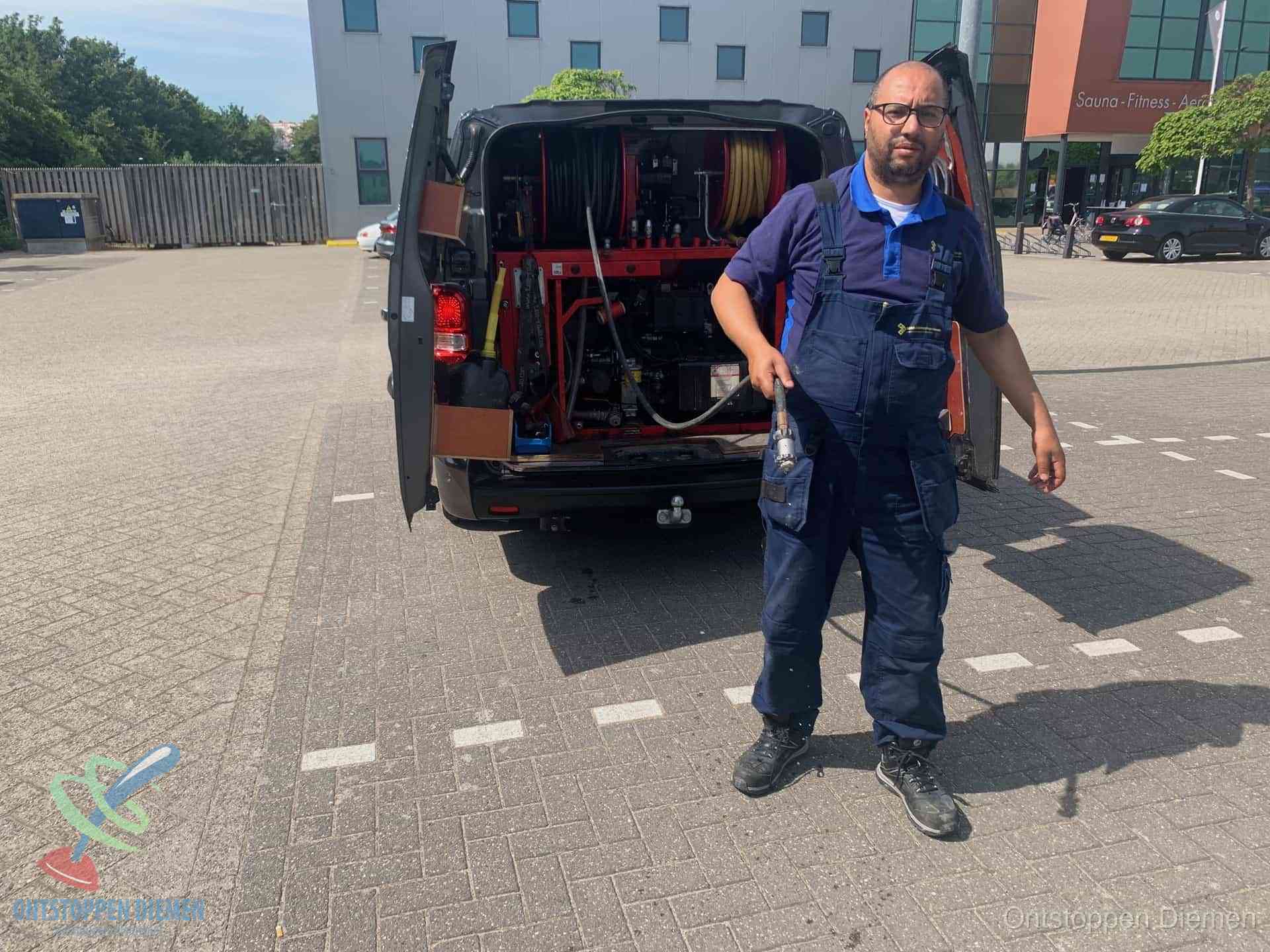 Een monteur bij zijn bestelbus met een hogedruk- en rioolreinigingsunit, klaar om de oorzaak van terugkerende wc-verstoppingen aan te pakken in Diemen