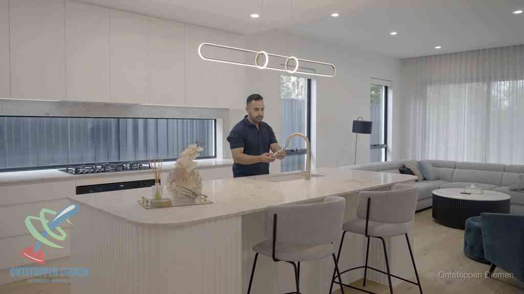 Een bewoner bij de keukenspoelbak die zelf aan de slag gaat met een verstopte gootsteen in Diemen